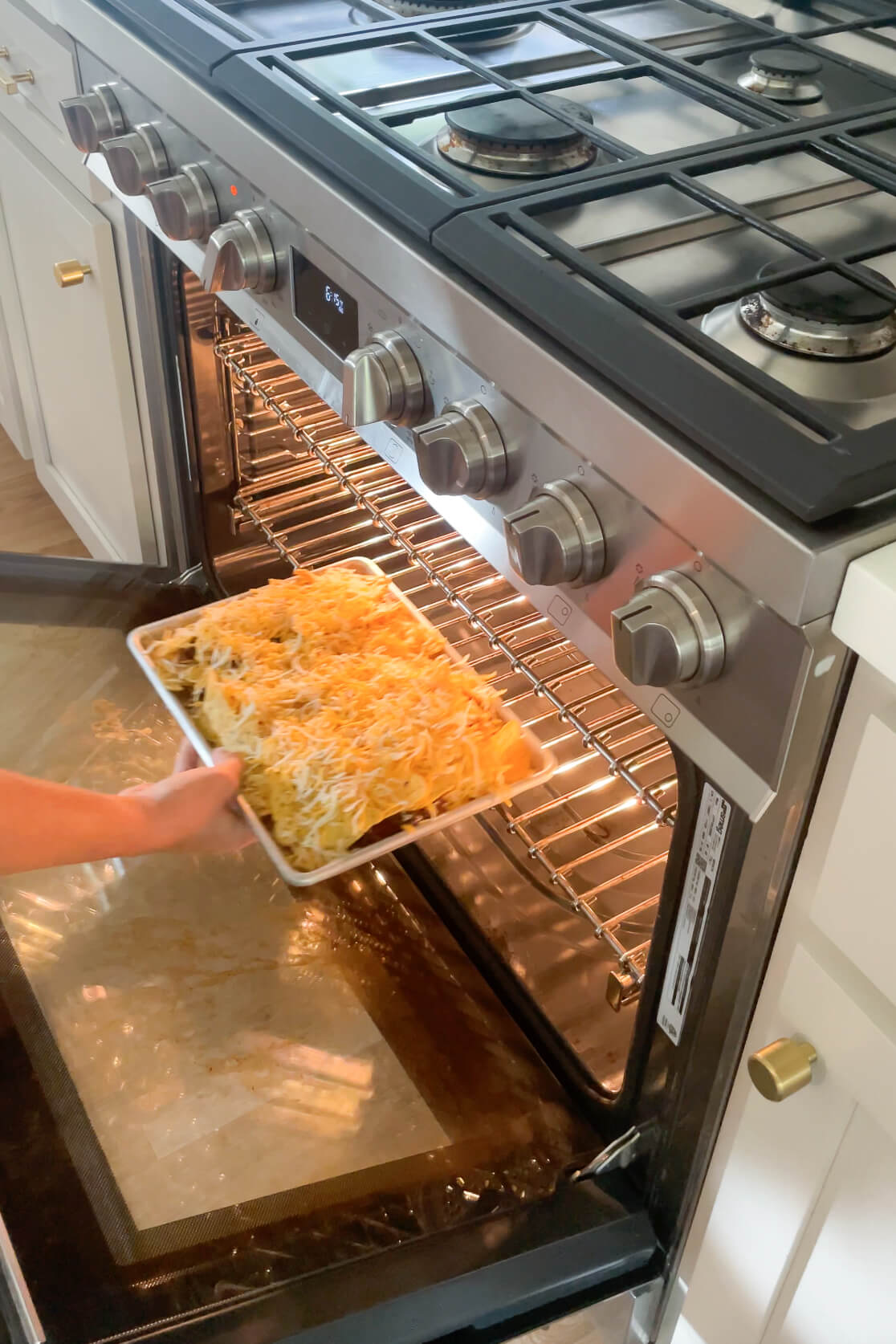 Melting cheese by putting the sheet pan nachos in the oven. 